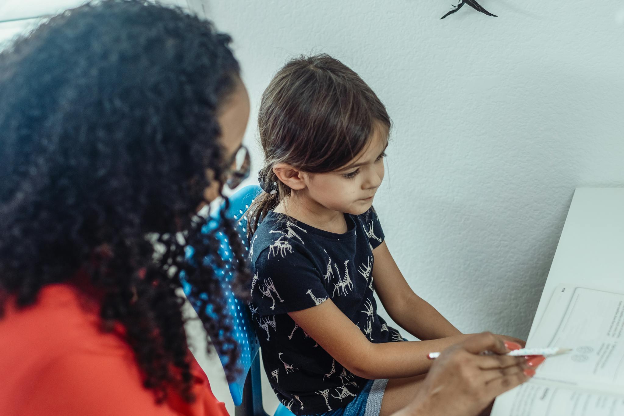 A young child in a learning session with a tutor at home, focused and engaged.